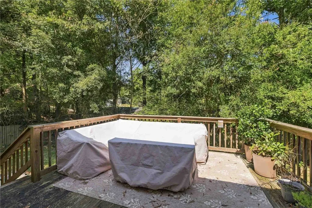 A spacious wooden deck overlooks a serene backdrop of mature trees.