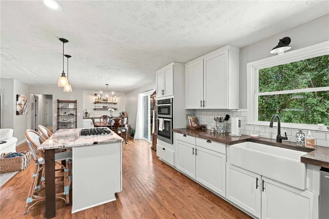 Rich hardwood flooring anchors this updated kitchen featuring stone countertops and an integrated island.