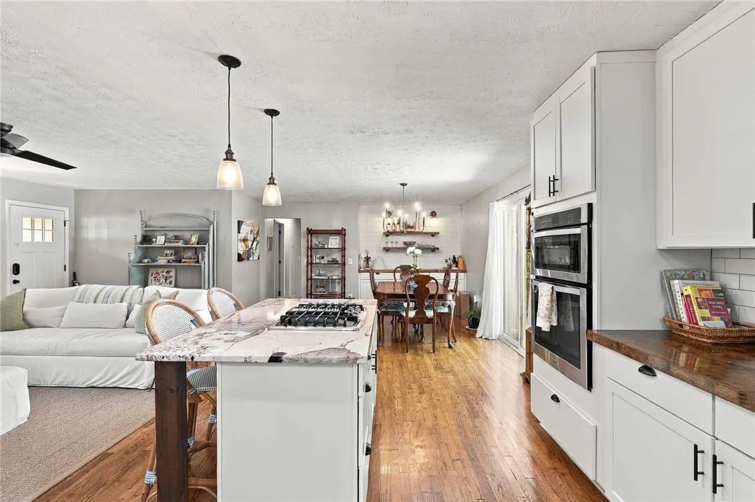 An open floorplan seamlessly connects the well-appointed kitchen to surrounding living areas over warm hardwood floors.