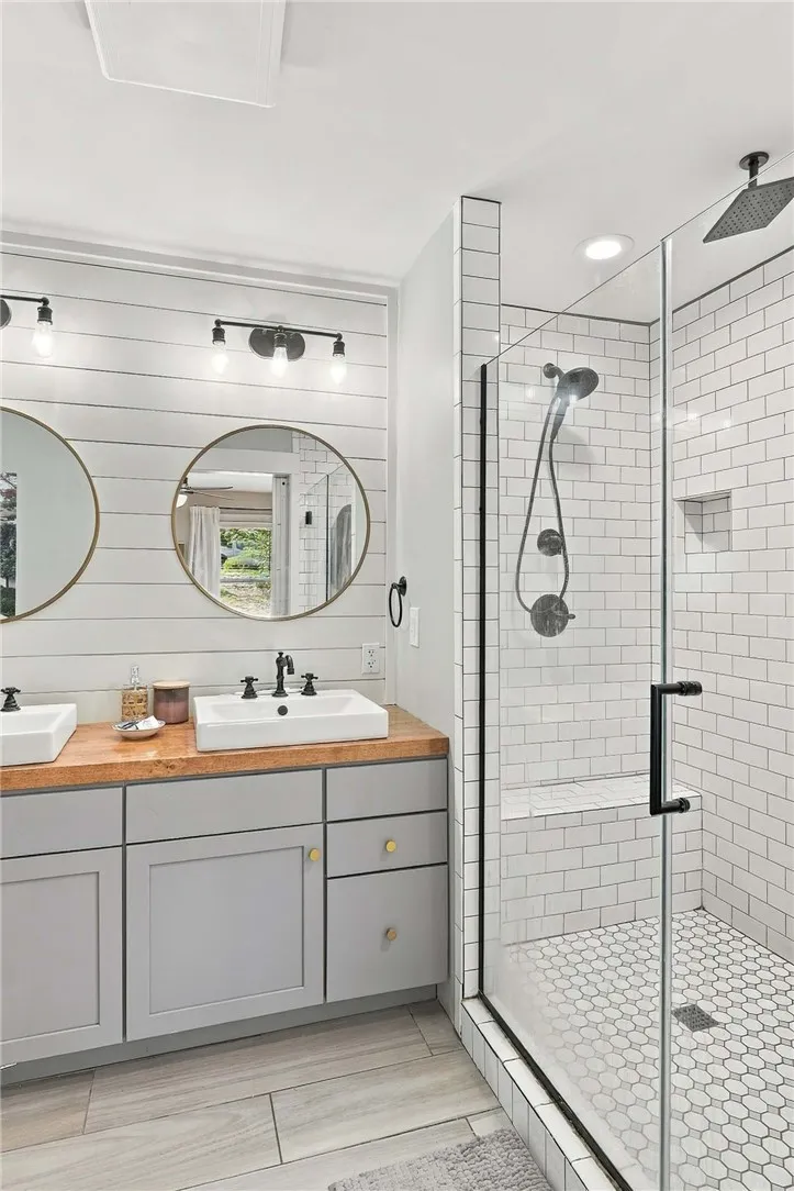 Clean lines and warm wood accents define this updated bathroom featuring a tiled walk-in shower.