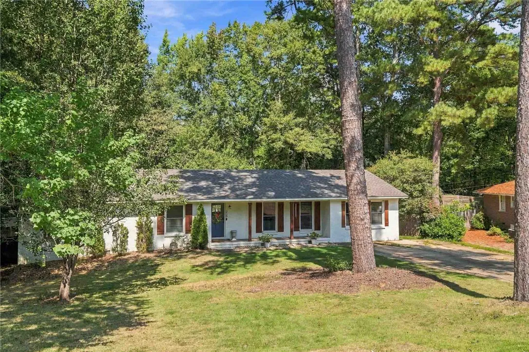 Mature trees frame a single-level home with a spacious front yard and classic brick details.