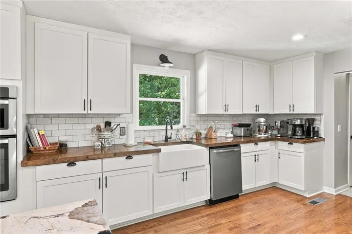 Rich wood countertops contrast beautifully with classic white cabinetry and hardwood flooring.