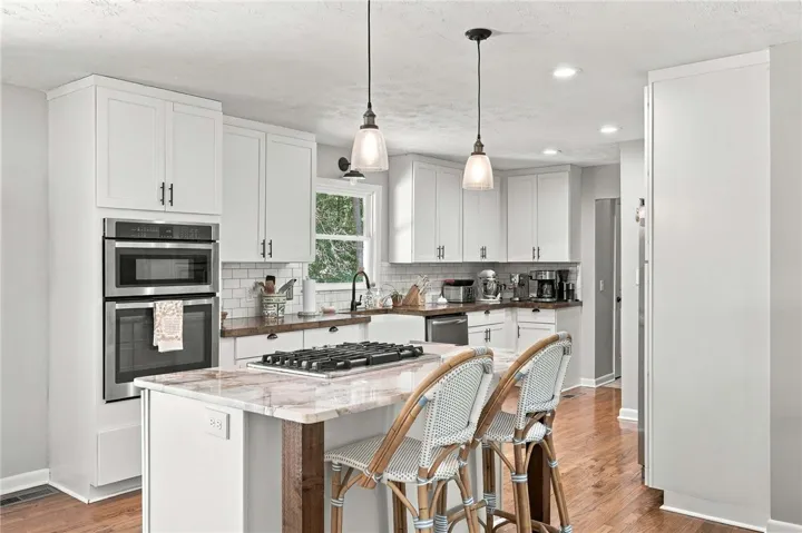 Polished stone countertops pair elegantly with classic shaker cabinetry and warm hardwood flooring.