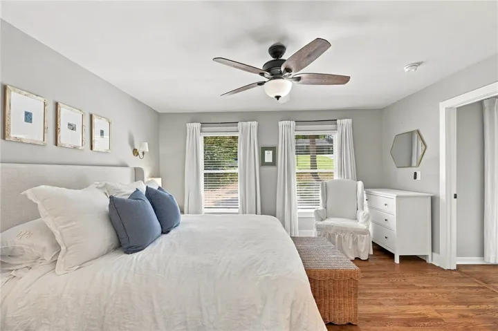 Rich hardwood flooring complements the smooth walls and abundant natural light in this spacious bedroom.