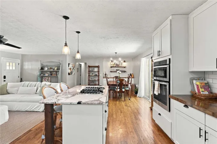 An open floorplan seamlessly connects the well-appointed kitchen to surrounding living areas over warm hardwood floors.