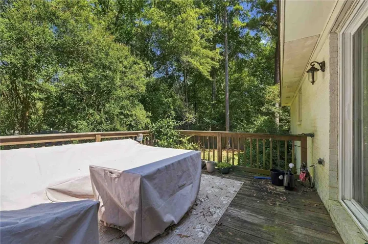 A spacious wooden deck overlooks a serene backyard surrounded by mature trees.