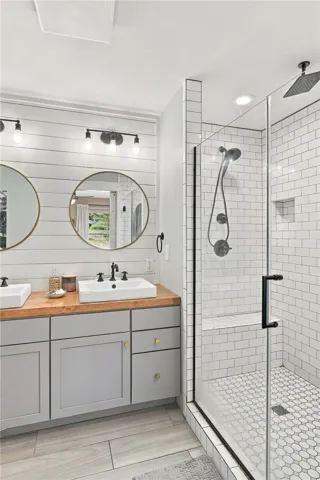 Clean lines and warm wood accents define this updated bathroom featuring a tiled walk-in shower.