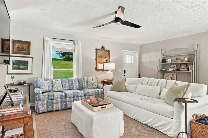 A bright living space features hardwood flooring and views of the surrounding green lawn.
