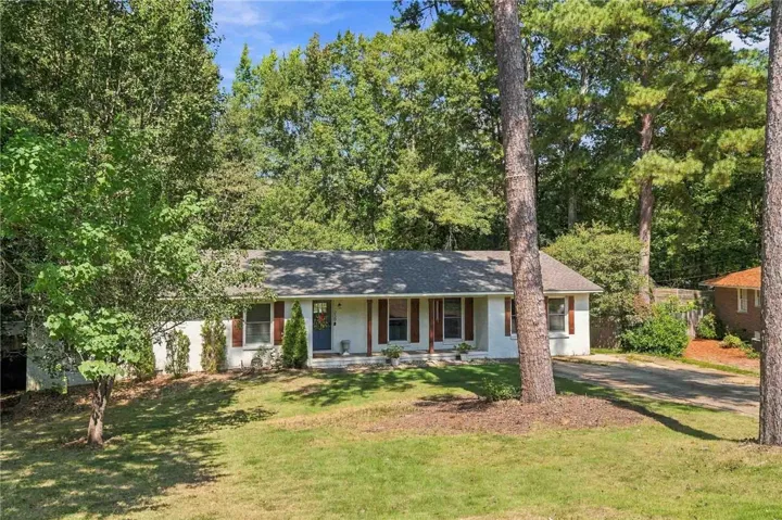 Mature trees frame a single-level home with a spacious front yard and classic brick details.