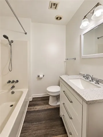 Rich wood-look flooring anchors this well-appointed bathroom complete with a stone vanity top.