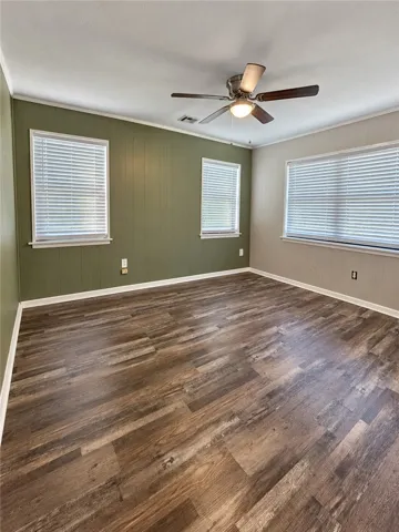 Rich wood-look flooring and multiple windows create a welcoming foundation in this versatile room.