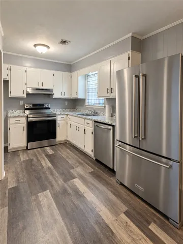 Classic cabinetry meets contemporary stainless steel appliances over rich wood-look flooring.