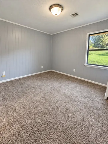 Plush carpeting and wood-paneled walls define this quiet bedroom looking out over the yard.