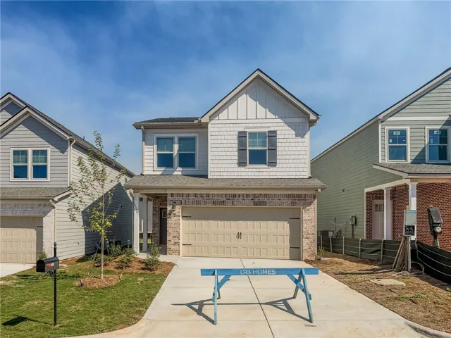 A classic two-story exterior integrates brick accents, neutral siding, and a spacious front-facing garage.