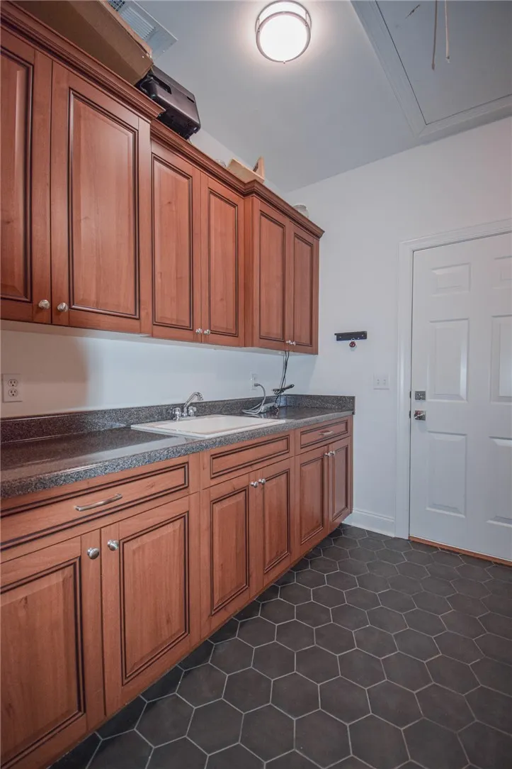 Rich wood cabinetry paired with dark hexagonal floor tiles creates a functional utility space.