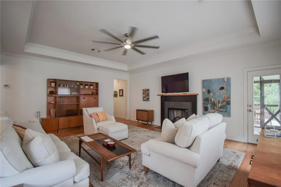 Crown molding and a tray ceiling elevate this inviting living space complete with a fireplace.