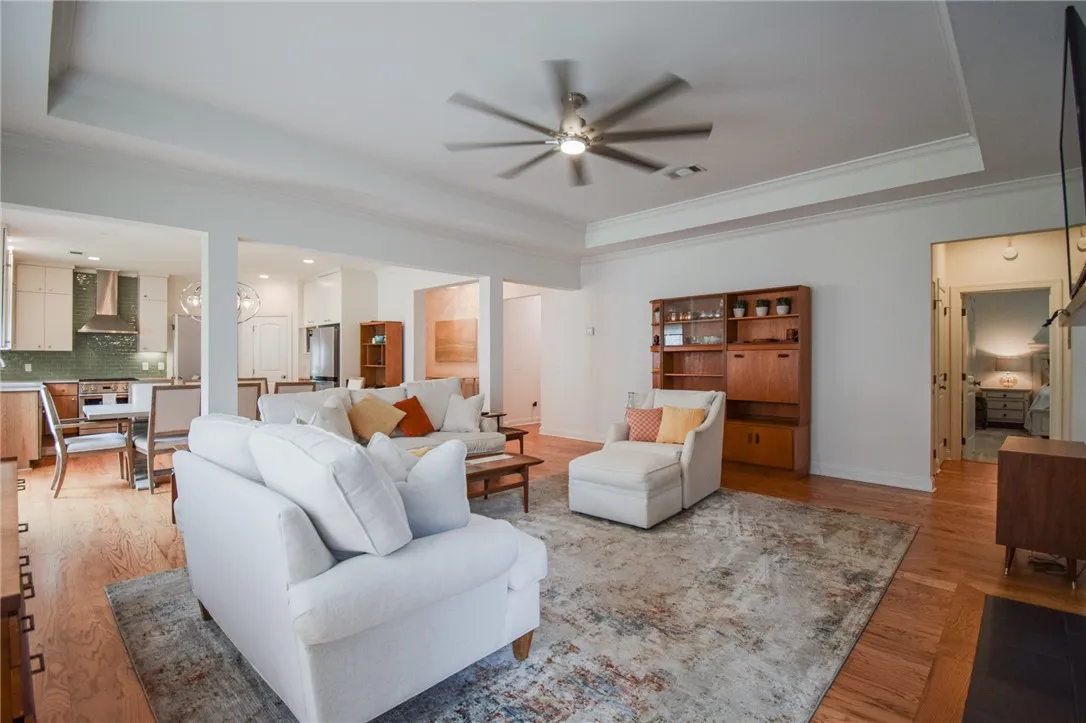 Warm hardwood floors and tray ceilings define this welcoming open-concept living space.