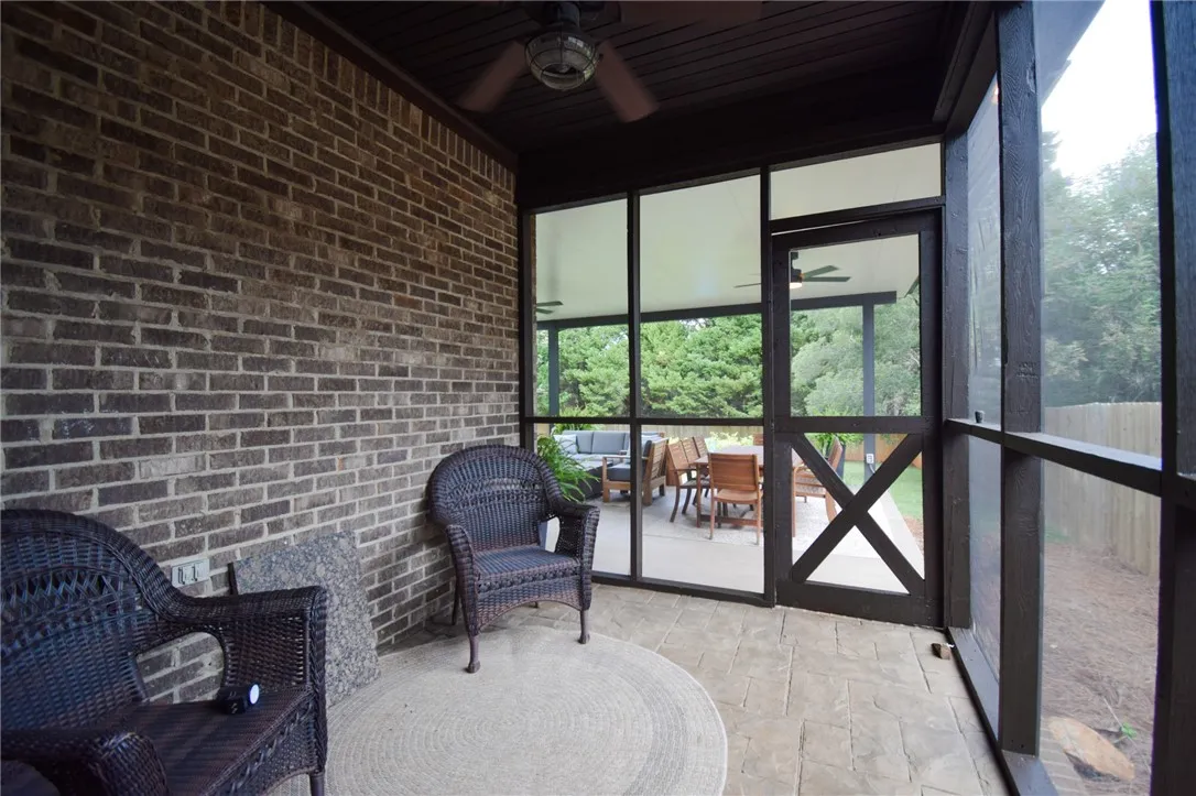 A screened porch features brick wall accents and stone paver flooring overlooking the backyard.