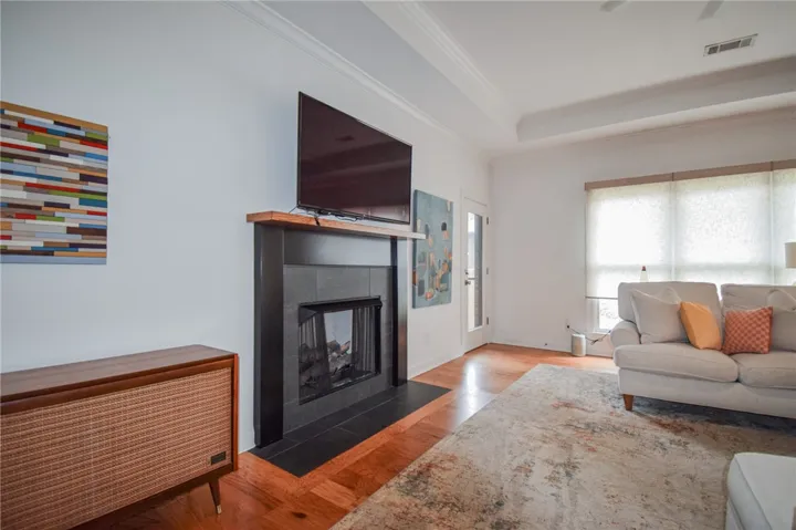Rich hardwood floors and a modern fireplace anchor this welcoming living area under recessed tray ceilings.