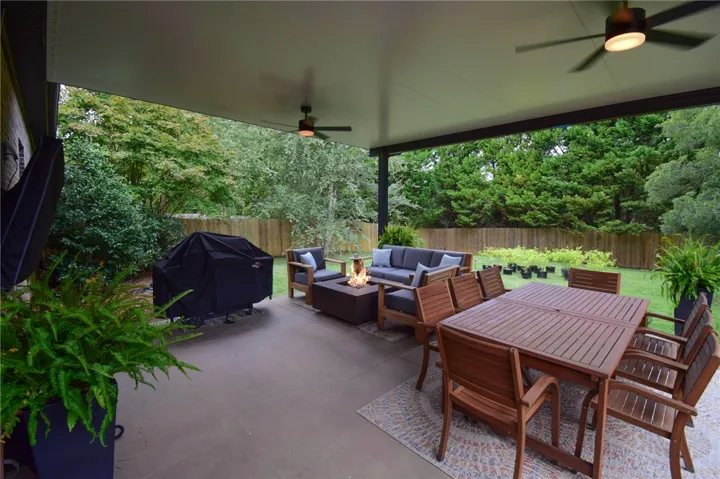 A spacious covered patio overlooks the fenced backyard complete with lush green lawns and mature trees.