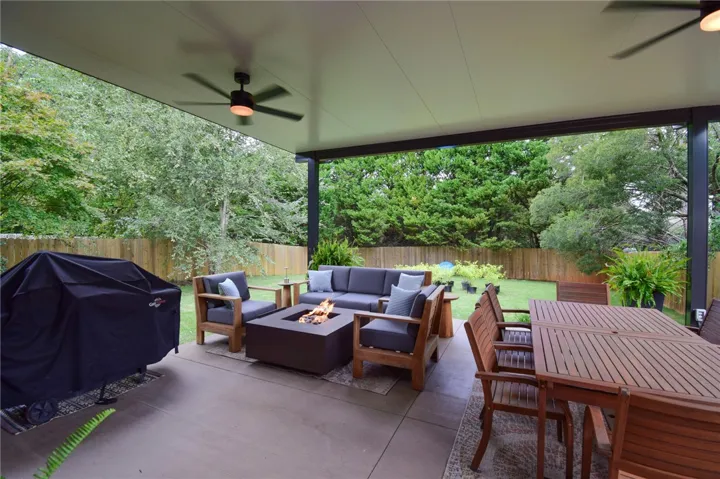 Sheltered outdoor living transitions smoothly to a grassy lawn enclosed by privacy fencing.