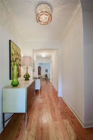 Rich wood flooring and classic crown molding guide the eye down this elegant hallway.