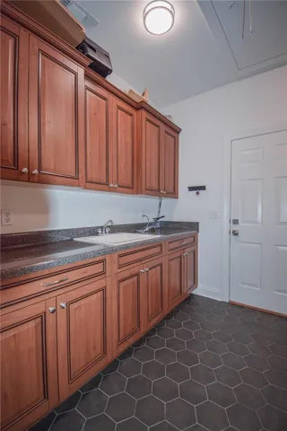 Rich wood cabinetry paired with dark hexagonal floor tiles creates a functional utility space.