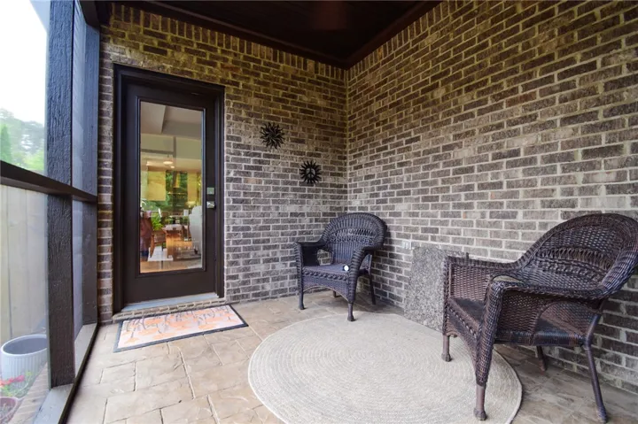 Rich brick walls and textured stone flooring highlight this inviting screened porch retreat.