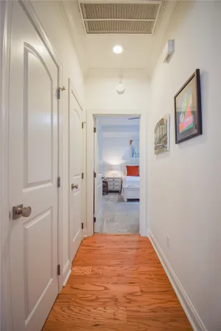 Warm hardwood flooring guides the eye through this classic hallway toward a carpeted bedroom.