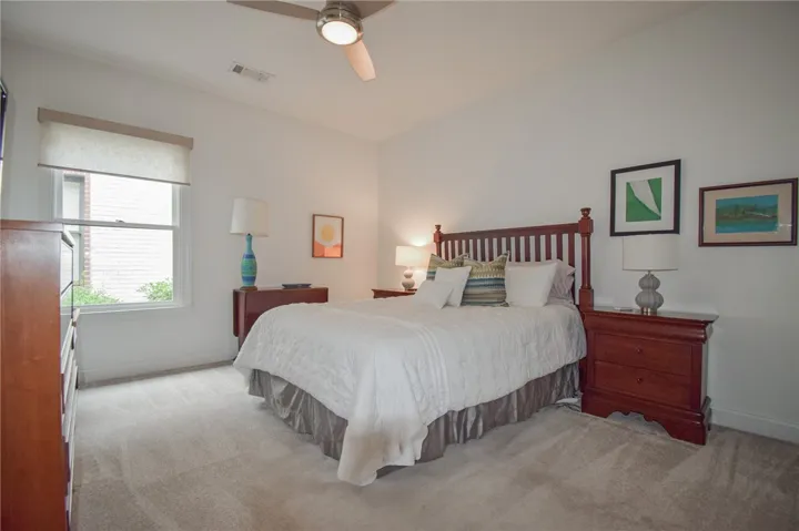 Soft carpeting pairs with a large window in this serene bedroom retreat.