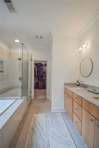 Crown molding and geometric floor tiles elevate this elegant bathroom with an adjacent closet.