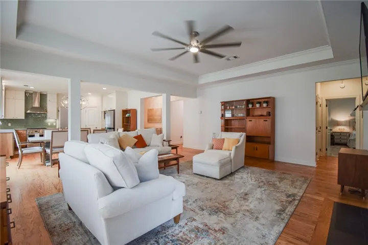 Warm hardwood floors and tray ceilings define this welcoming open-concept living space.