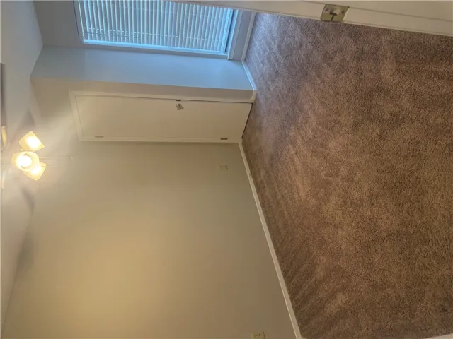 Soft carpeting pairs with neutral walls and a tall window in this versatile bedroom 2.
