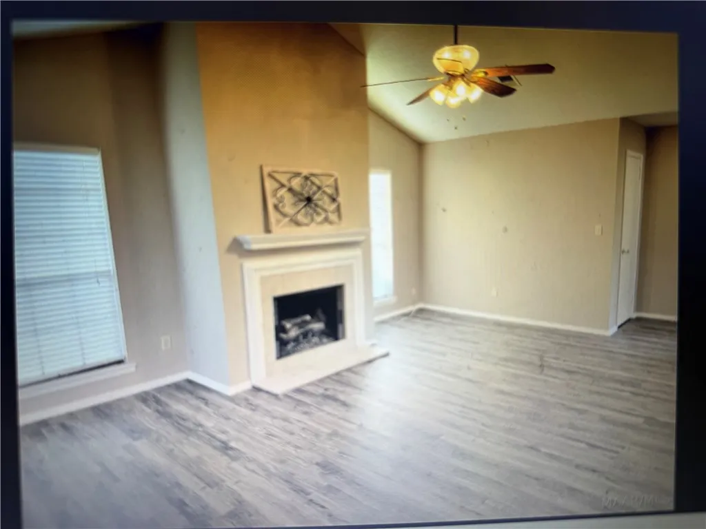A classic fireplace anchors this airy living space complete with laminated flooring and vaulted ceilings.