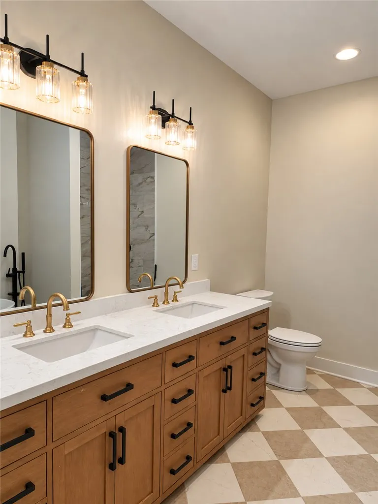 Gleaming stone countertops and warm wood cabinetry anchor this elegant bathroom space.