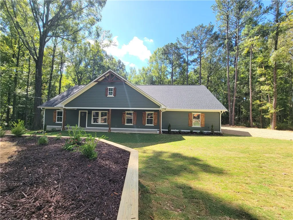 A classic facade features rustic wood shutters set against clean siding and a manicured lawn.