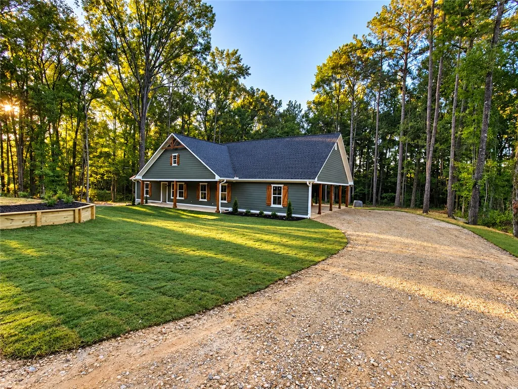 Towering trees frame a gravel driveway leading to this craftsman home with custom board shutters.