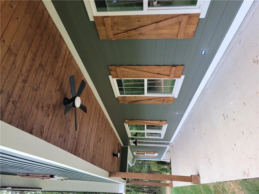 Rich wood plank ceilings and matching shutters elevate this welcoming concrete porch.
