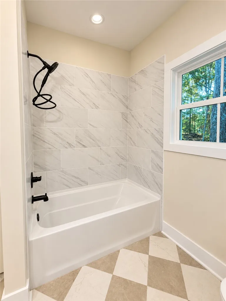 Elegant tiled tub surrounds complement patterned flooring and modern black fixtures.