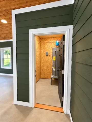 An organized utility closet displays clean-finished concrete floors and a wood-paneled ceiling overhead.