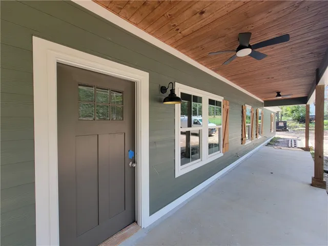 Rich wood plank ceilings shelter a spacious concrete porch featuring classic board shutters.
