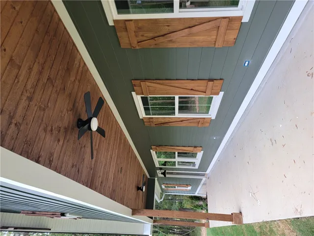 Rich wood plank ceilings and matching shutters elevate this welcoming concrete porch.