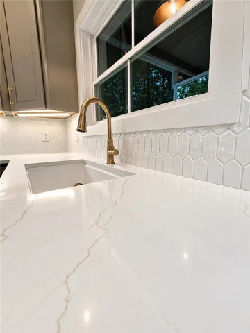 Elegant stone countertops pair beautifully with a classic tiled backsplash and modern gold fixtures.