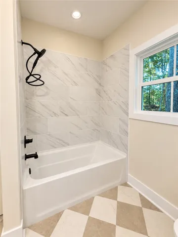 Elegant tiled tub surrounds complement patterned flooring and modern black fixtures.
