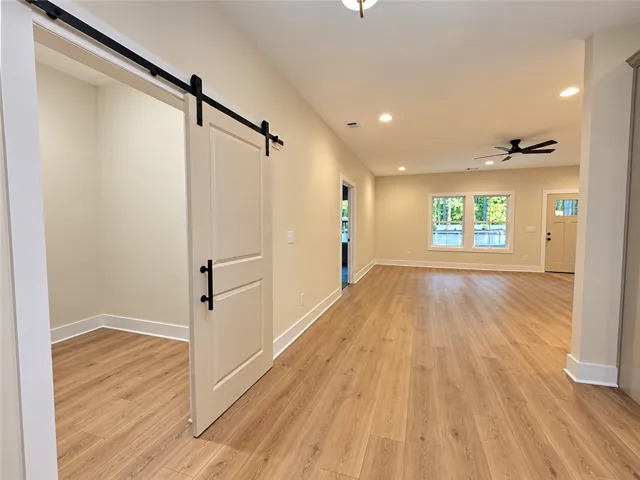Gleaming wood-look floors anchor a versatile open layout connected by an elegant sliding barn door.