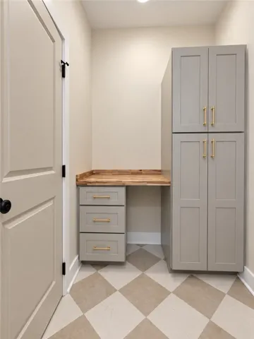 A built-in desk and matching tall cabinetry pair with checkered tile flooring in this functional space.