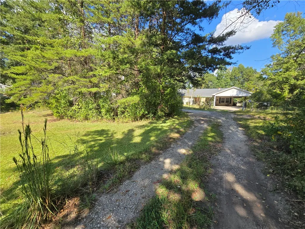 A long driveway winds past mature trees toward the welcoming entry of this secluded home.