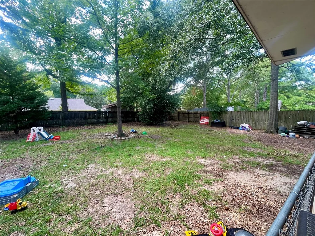 Mature trees frame a spacious, fully fenced yard offering plentiful outdoor possibilities.