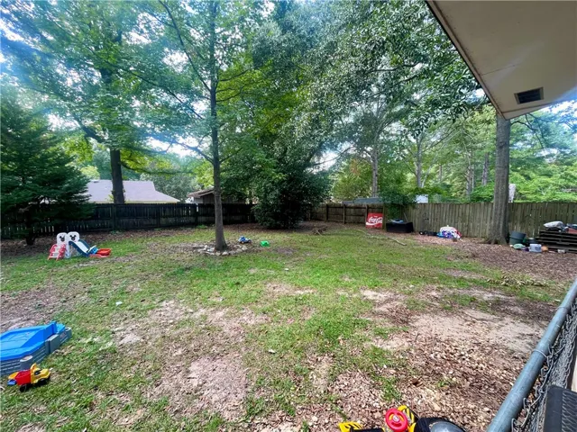 Mature trees frame a spacious, fully fenced yard offering plentiful outdoor possibilities.