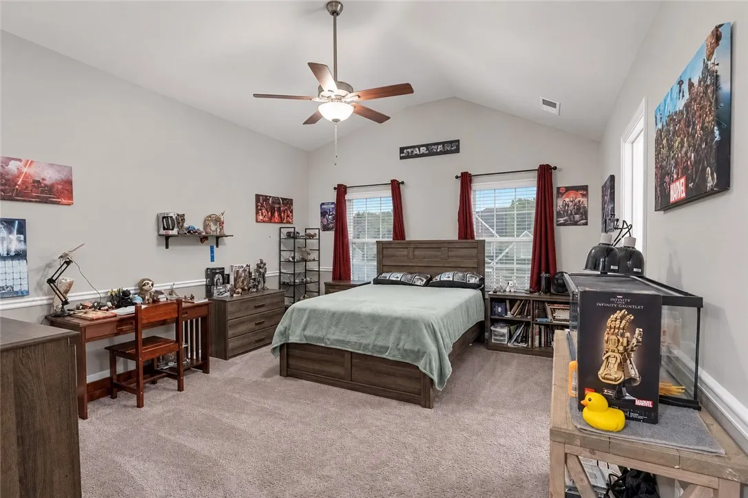 Vaulted ceilings and neutral carpeting define this comfortable secondary bedroom.